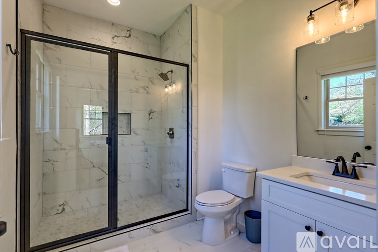 A bathroom with a marble shower and a white toilet.
