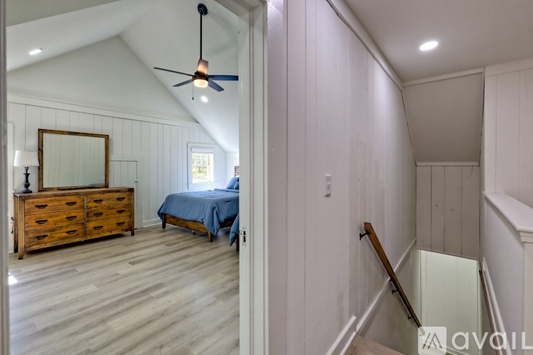 A bedroom with a bed, dresser, mirror, and a ceiling fan.