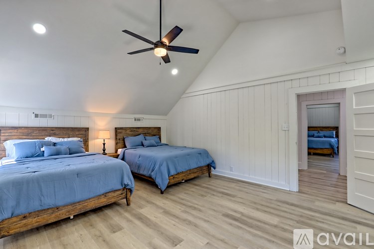 Two beds in a room with wooden floors and white walls.
