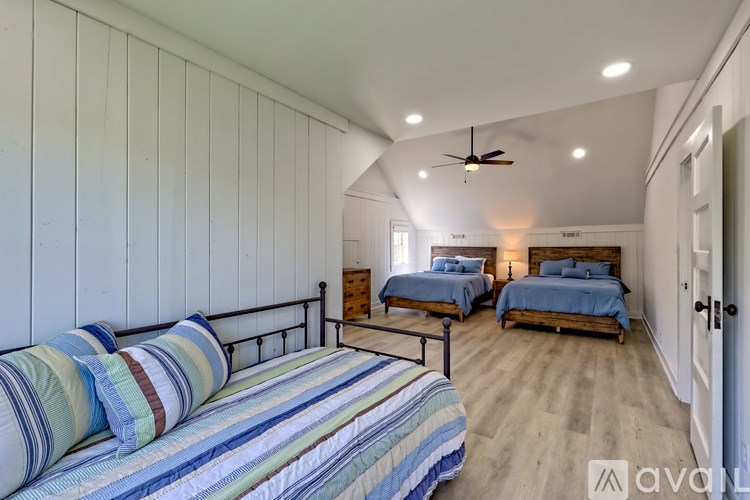 A bedroom with two beds and striped bedding.