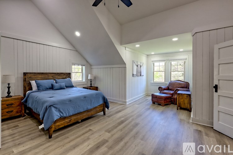 A bedroom with a bed, chair, and window.