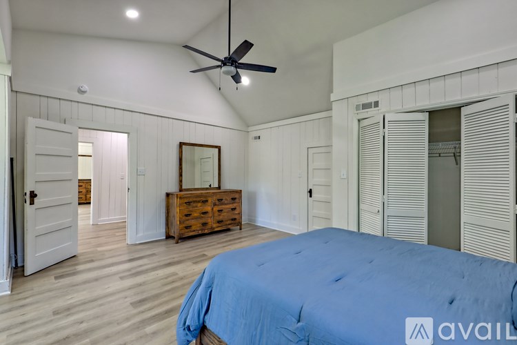A bedroom with a blue bedspread and a ceiling fan.