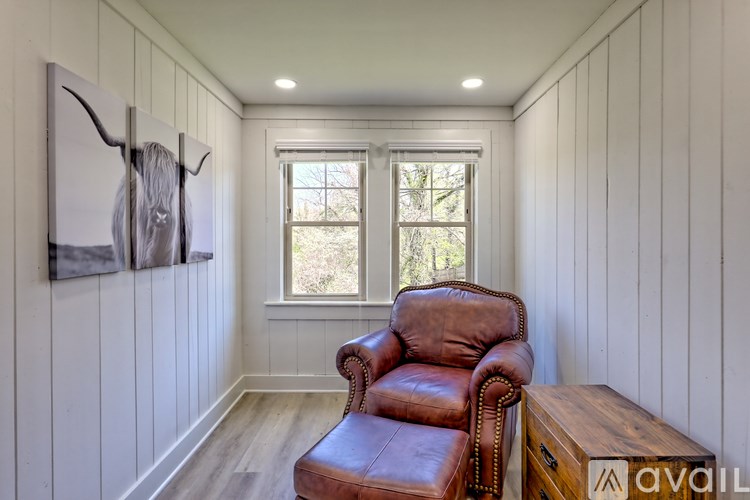 A room with a brown leather chair and a painting of a bull on the wall.