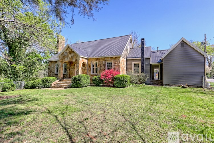 A house with a grey roof and a grey garage is surrounded by green grass and trees.