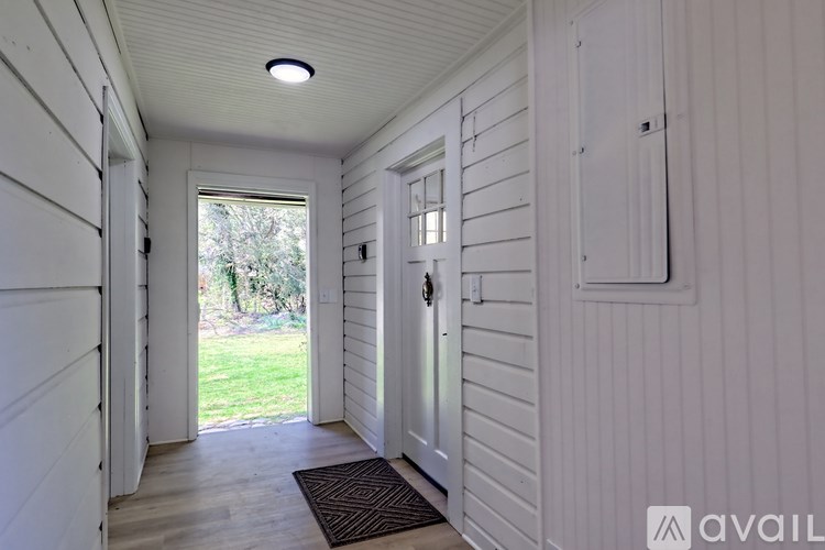 A hallway with white walls and a door leading to a backyard.