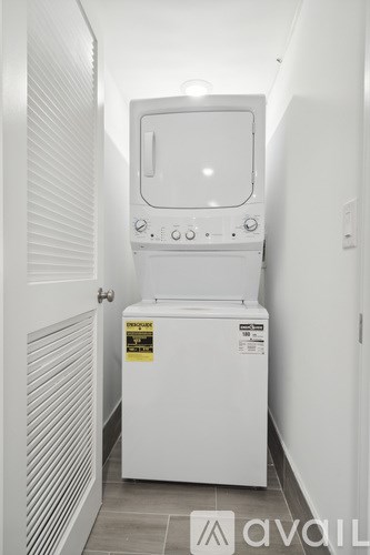 A white washing machine is in a narrow hallway.