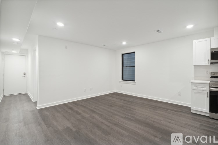A spacious room with wooden flooring and white walls.