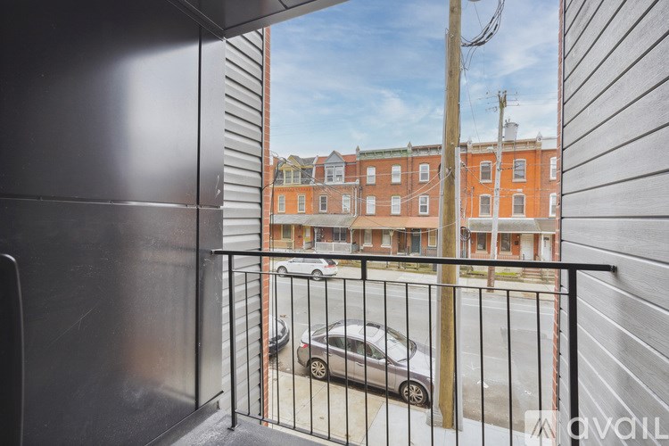 A balcony with a black railing and a car parked on the street.