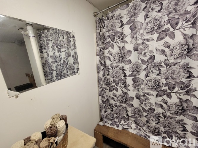 A bathroom with a floral shower curtain and a mirror.