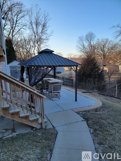 A gazebo is situated in a backyard with a deck and patio.
