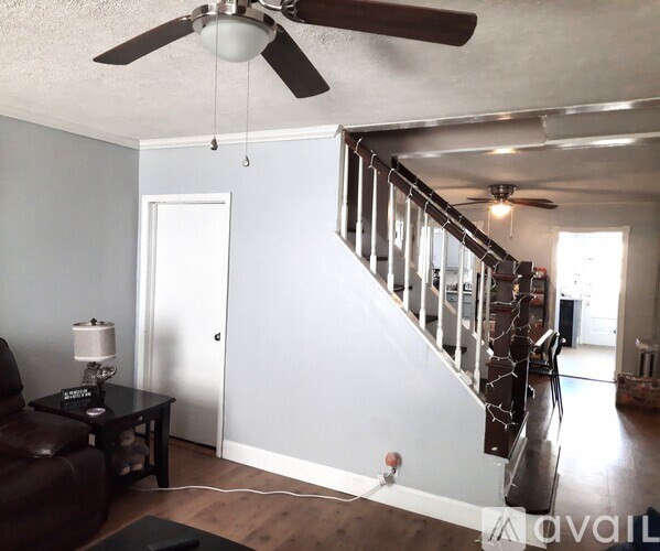 A living room with a brown leather couch and a ceiling fan.