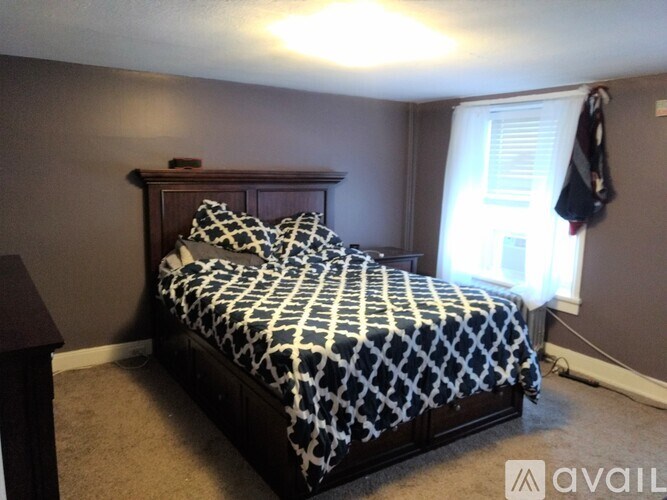 A bedroom with a bed covered in a black and white patterned comforter.