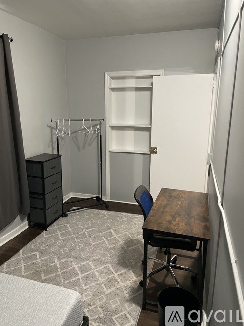 A room with a desk, chair, and a wardrobe.
