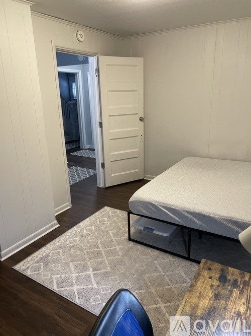 A bedroom with a bed, a rug, and a door leading to a hallway.