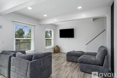 A living room with grey couches and a flat screen TV mounted on the wall.
