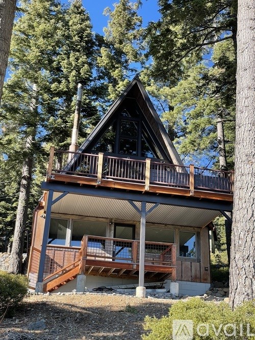A wooden cabin with a balcony is surrounded by trees.