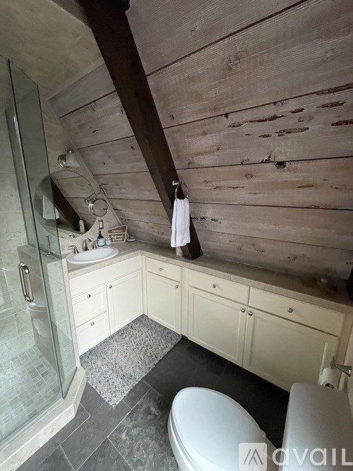 A bathroom with a wooden wall and a white toilet.