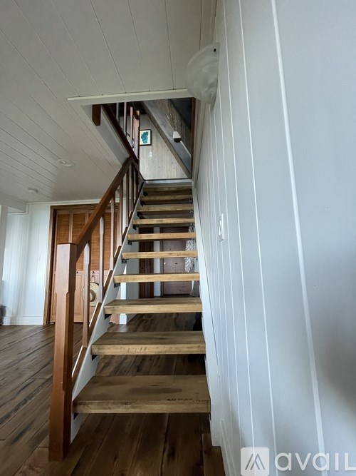 A wooden staircase with a white wall on one side.
