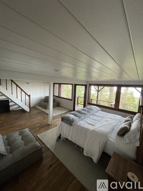 A bedroom with a bed, a couch, and a staircase.