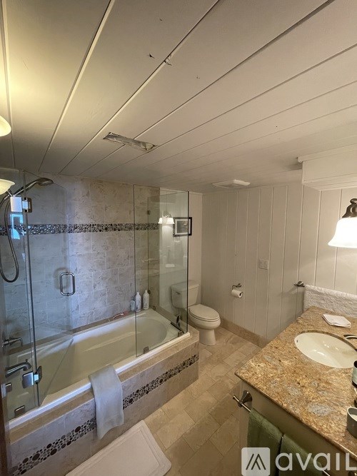 A bathroom with a glass shower stall, toilet, and sink.