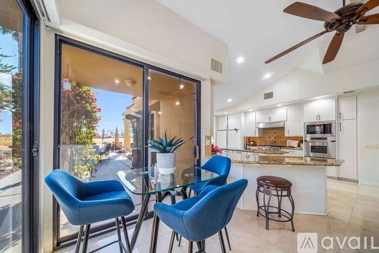 A modern kitchen with blue chairs and a glass table.