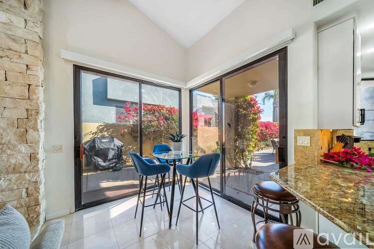 A kitchen area with a table and chairs in front of a glass door.