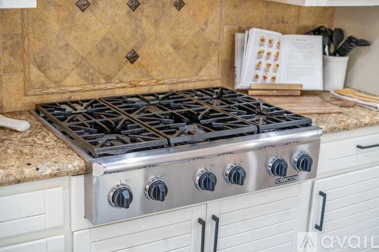 A modern kitchen with a stainless steel gas stove and white cabinets.