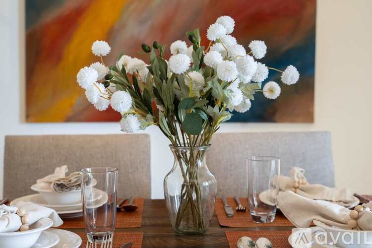 A table set for a meal with a vase of white flowers in the center.