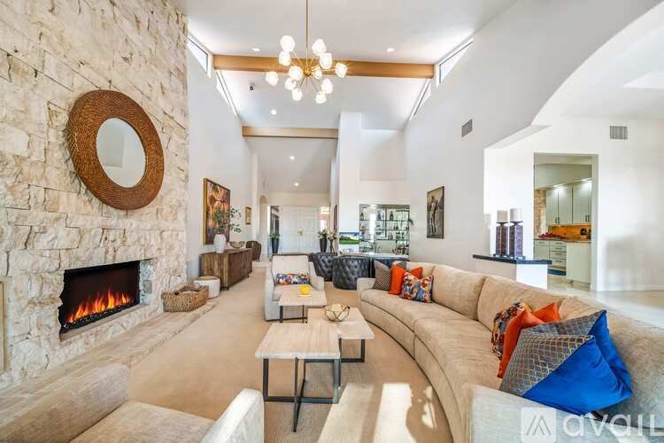 A living room with a stone fireplace and a large mirror on the wall.