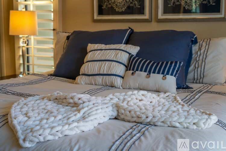 A bed with a white knitted throw on it.