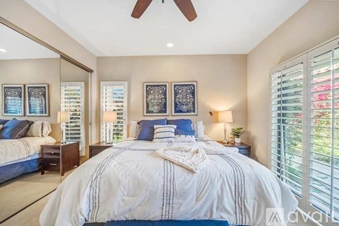 A bedroom with a large bed and a ceiling fan.