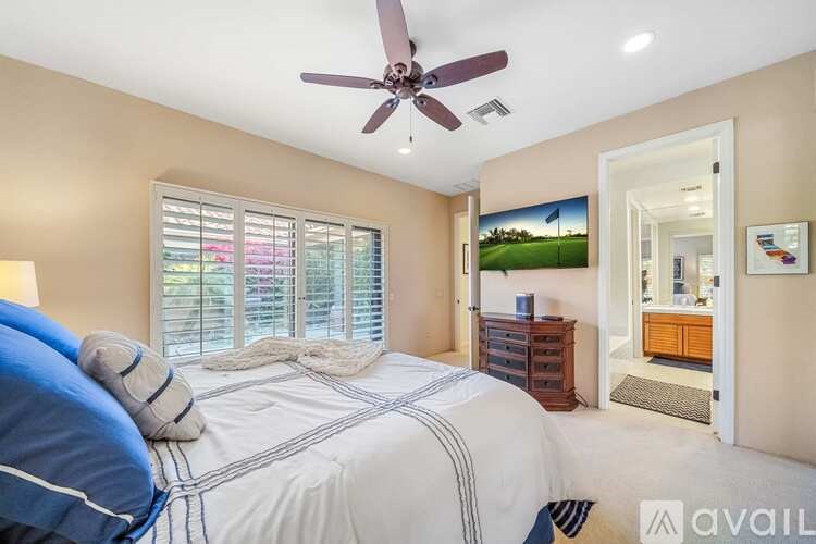 A bedroom with a large bed and a ceiling fan.