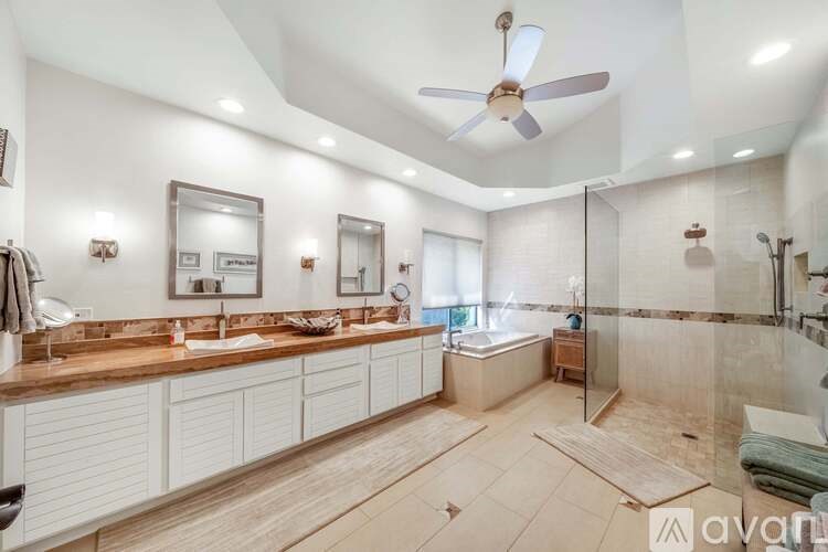 A spacious bathroom with a large mirror, double sinks, and a walk-in shower.