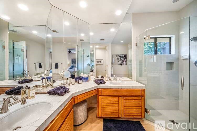 A modern bathroom with a large mirror and a wooden vanity.