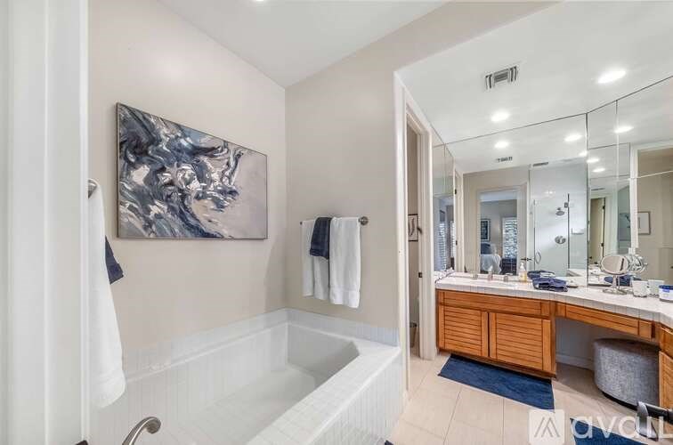 A bathroom with a white tub and a painting on the wall.