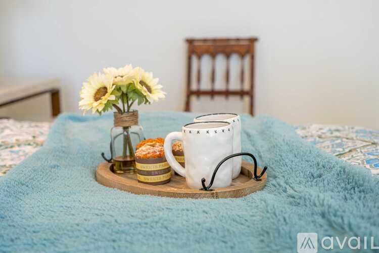 A tray with a coffee mug, a vase with flowers, and a pair of glasses on it.