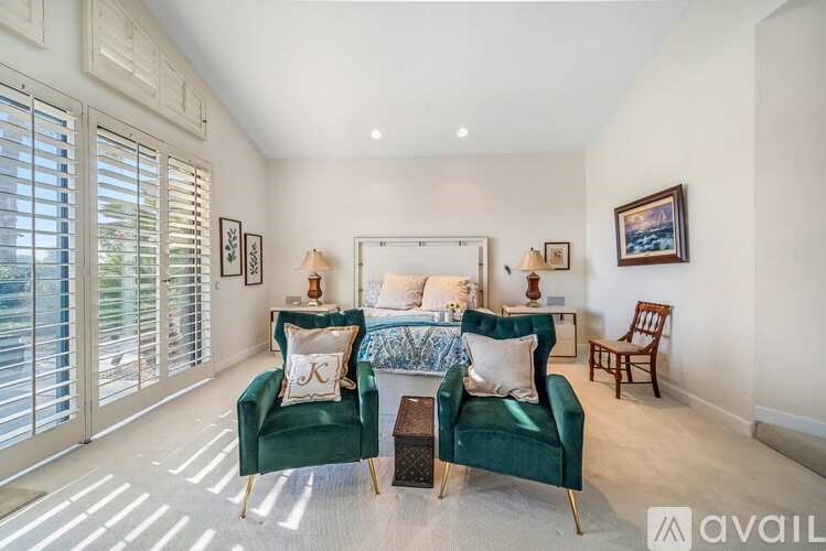 A living room with green chairs and a white bed.