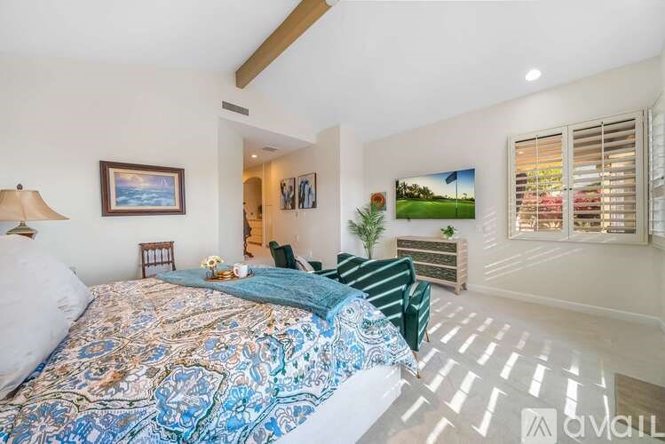 A bedroom with a large bed and a painting of a green field on the wall.