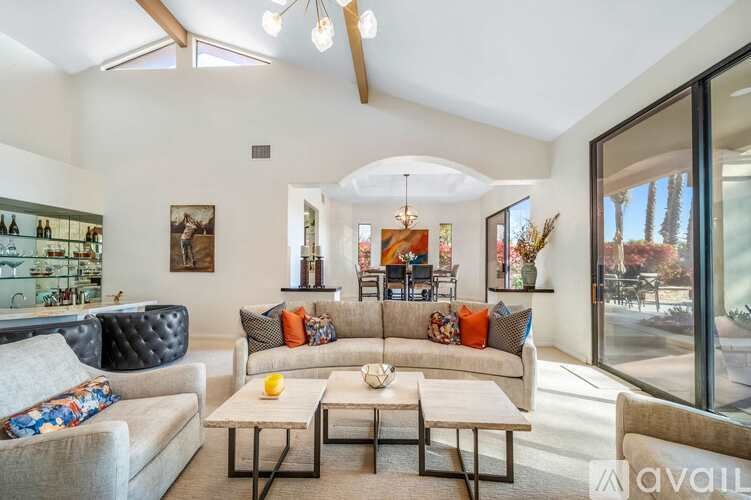 A living room with a black leather chair and a white couch with a coffee table in front of it.