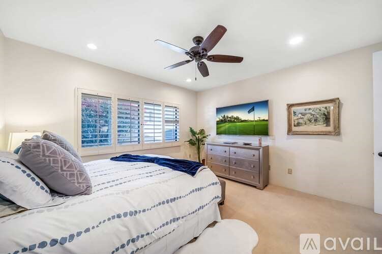 A bedroom with a bed, dresser, and a ceiling fan.