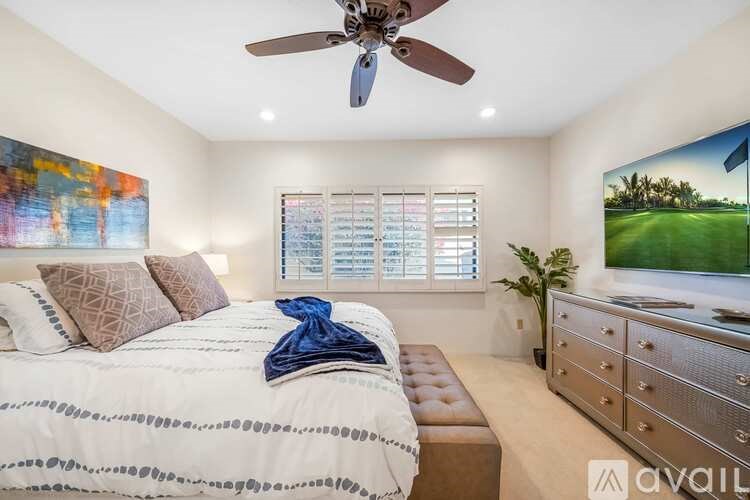A bedroom with a bed, dresser, and a ceiling fan.