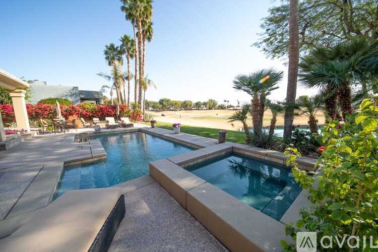 A pool surrounded by palm trees and a mountain in the distance.