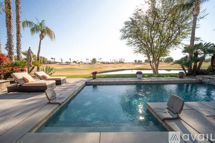 A pool with a chair and a tree in the background.