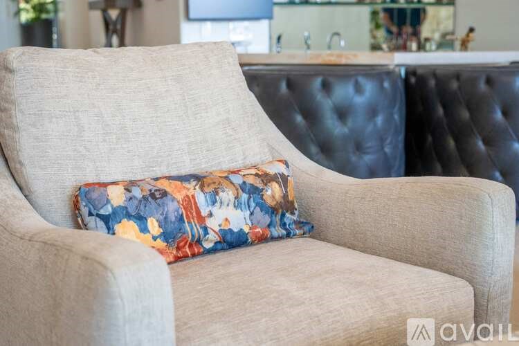 A beige armchair with a floral pillow is in the foreground.