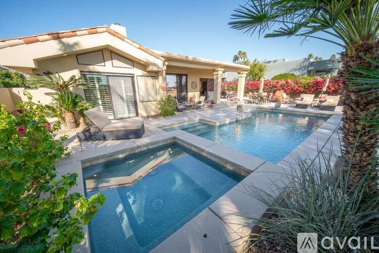 A pool in a backyard with a house in the background.