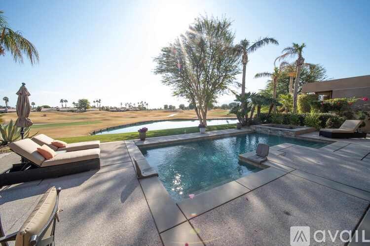 A pool surrounded by a patio and trees.