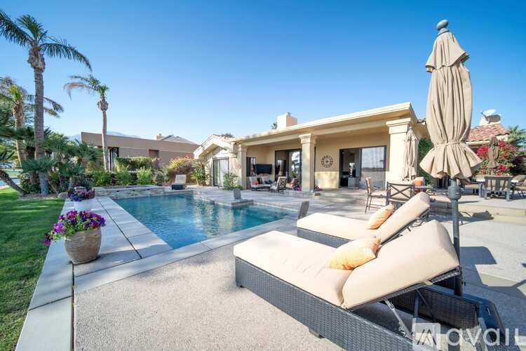 A poolside patio with a sun lounger and a large umbrella.