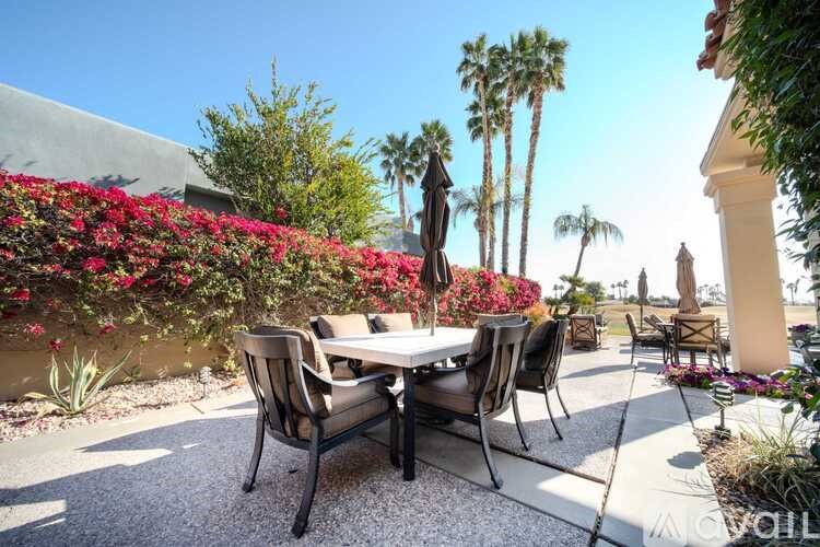 A table surrounded by chairs is in the middle of a patio.