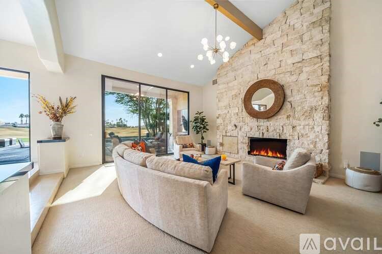 A living room with a stone fireplace and a large mirror above it.