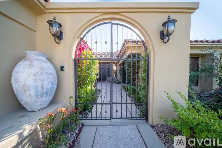 A large white vase sits on a patio next to a gate.